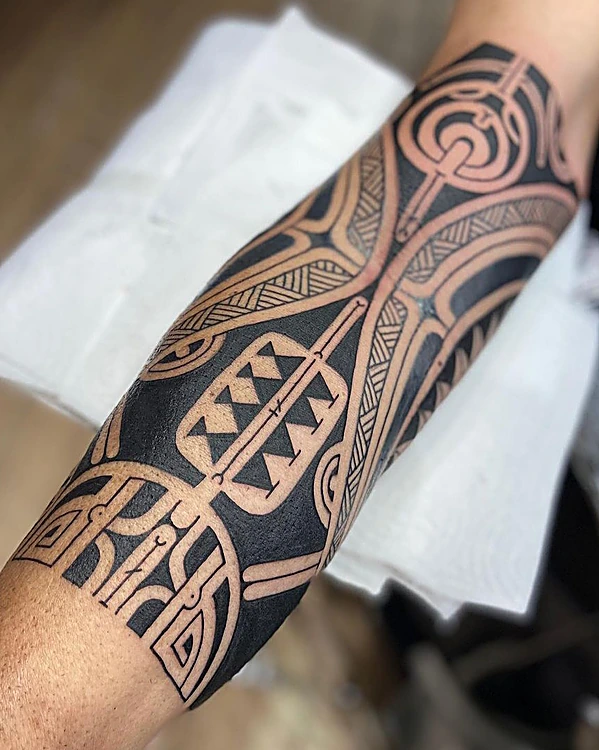Tatuaje tribal de estilo polinesio en negro sólido que envuelve el antebrazo